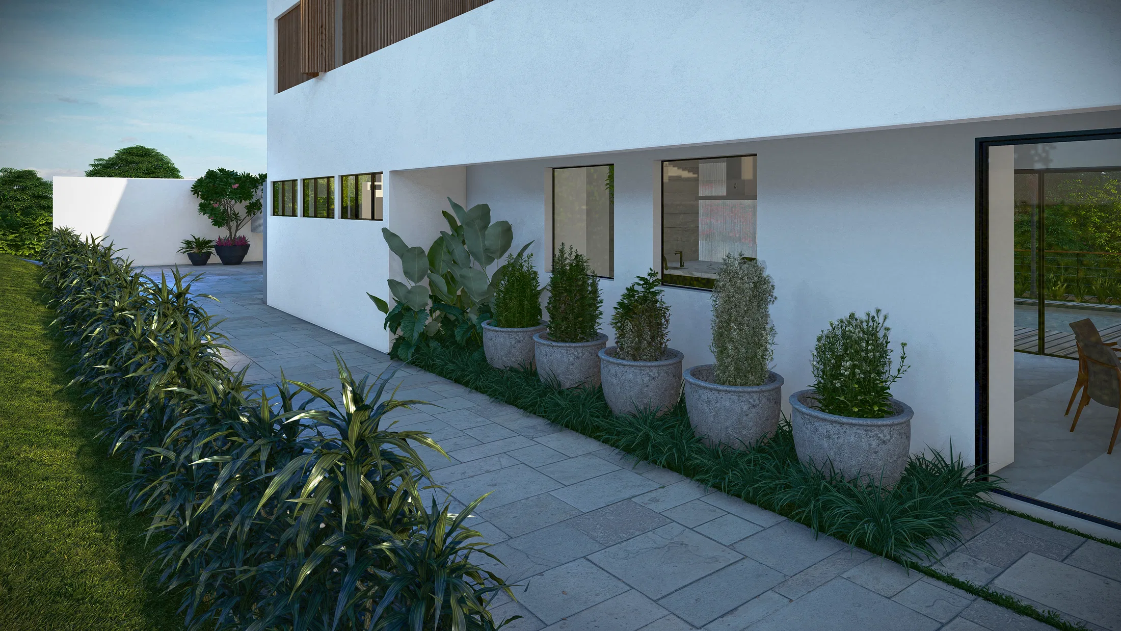 Side of the white façade with a row of tall planters and a linear foliage bed running along the concrete-paver path