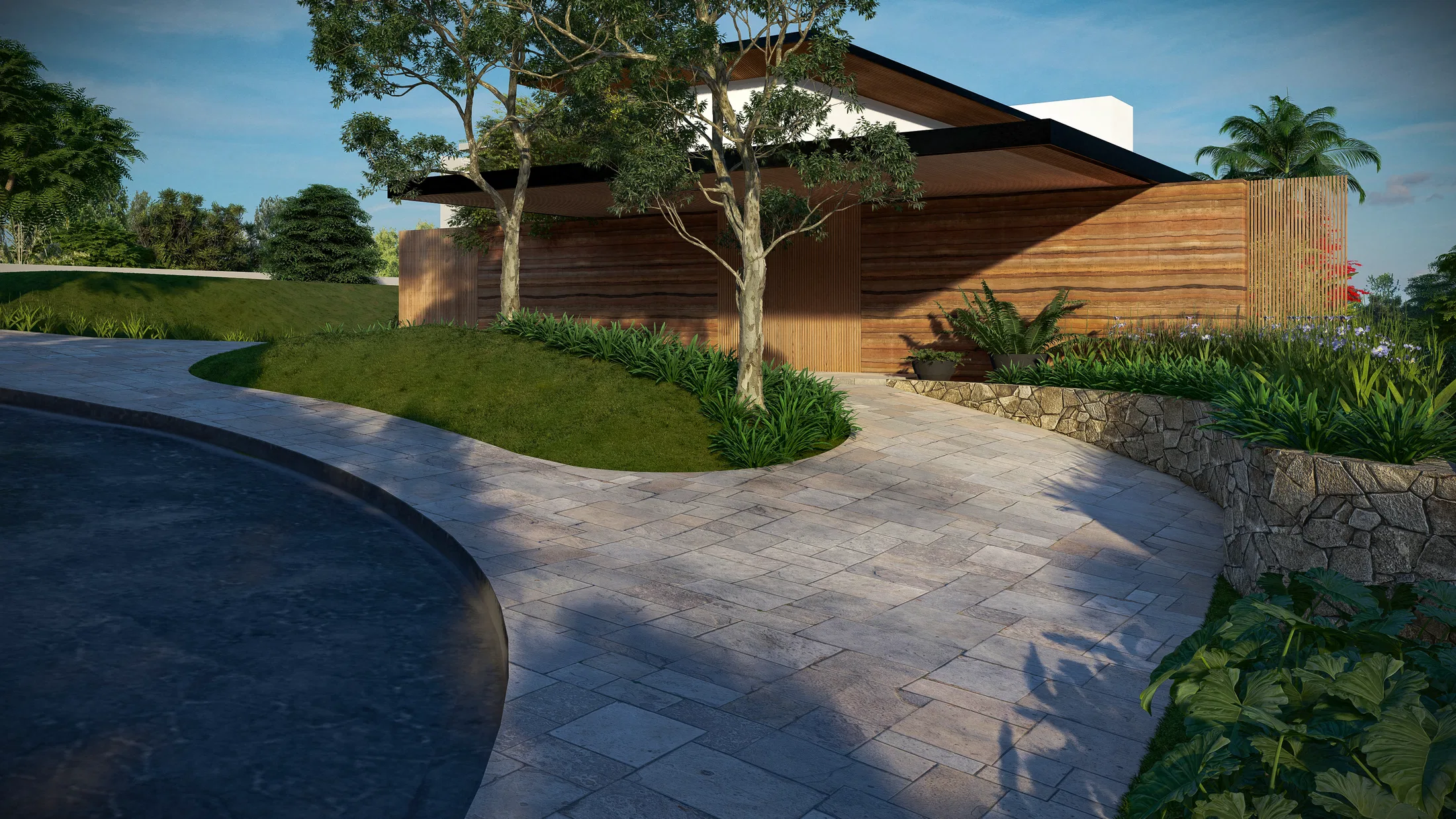 Curved stone-paved driveway with a stone retaining wall and planted beds in front of the timber-slat façade