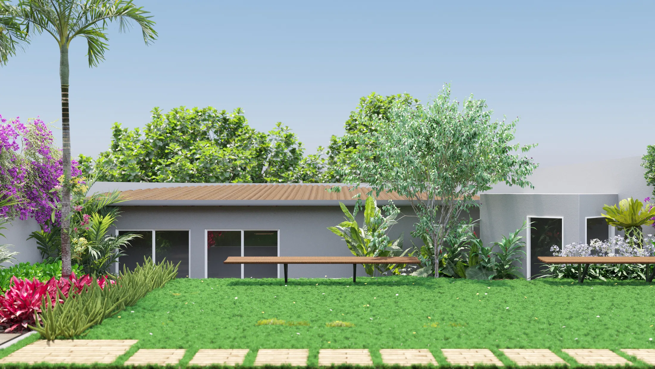 Rear of a single-storey house with a broad lawn, wooden benches, a palm at left and tropical beds along the facade.