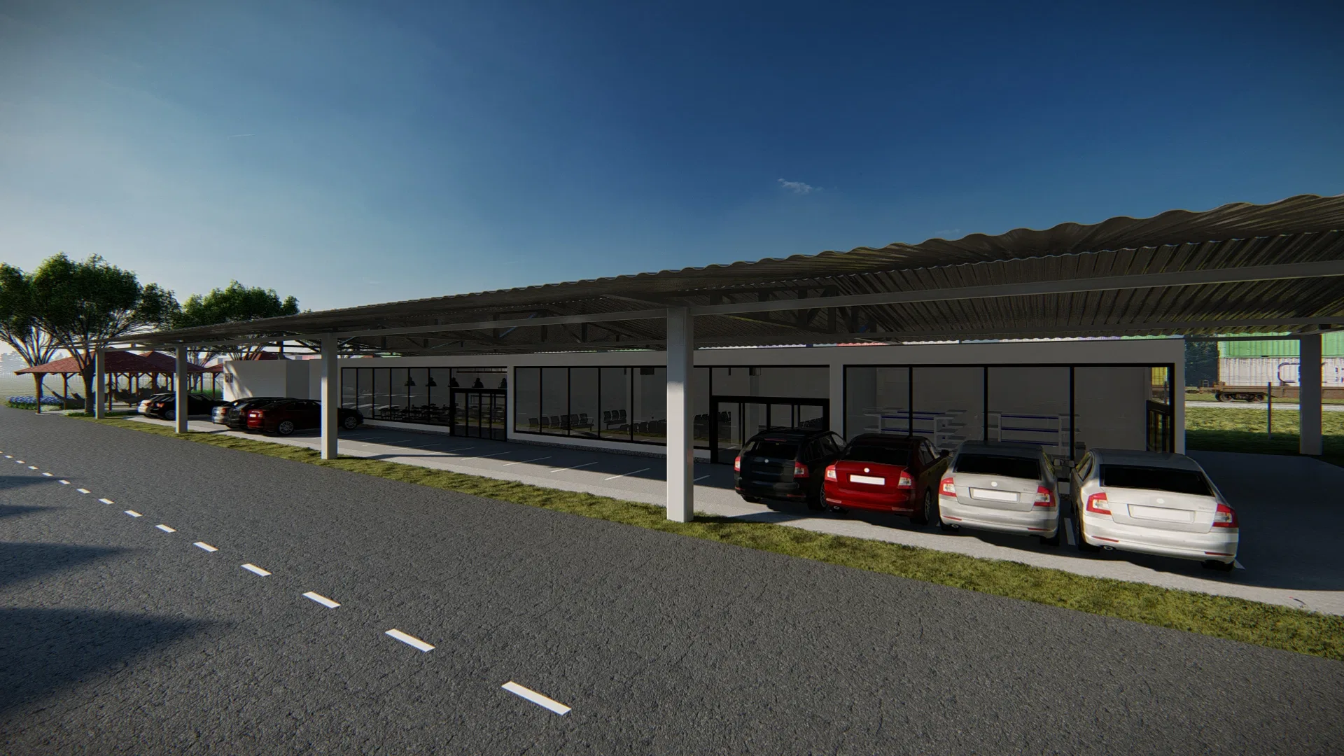 A long metal canopy on white columns sheltering a row of cars, in front of a low glazed block and a strip of grass