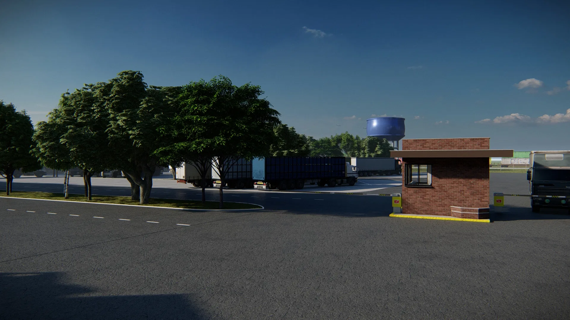 Facility entrance with a brick gatehouse and barrier, an asphalt yard with parked trailers, shade trees and a raised blue water tower behind