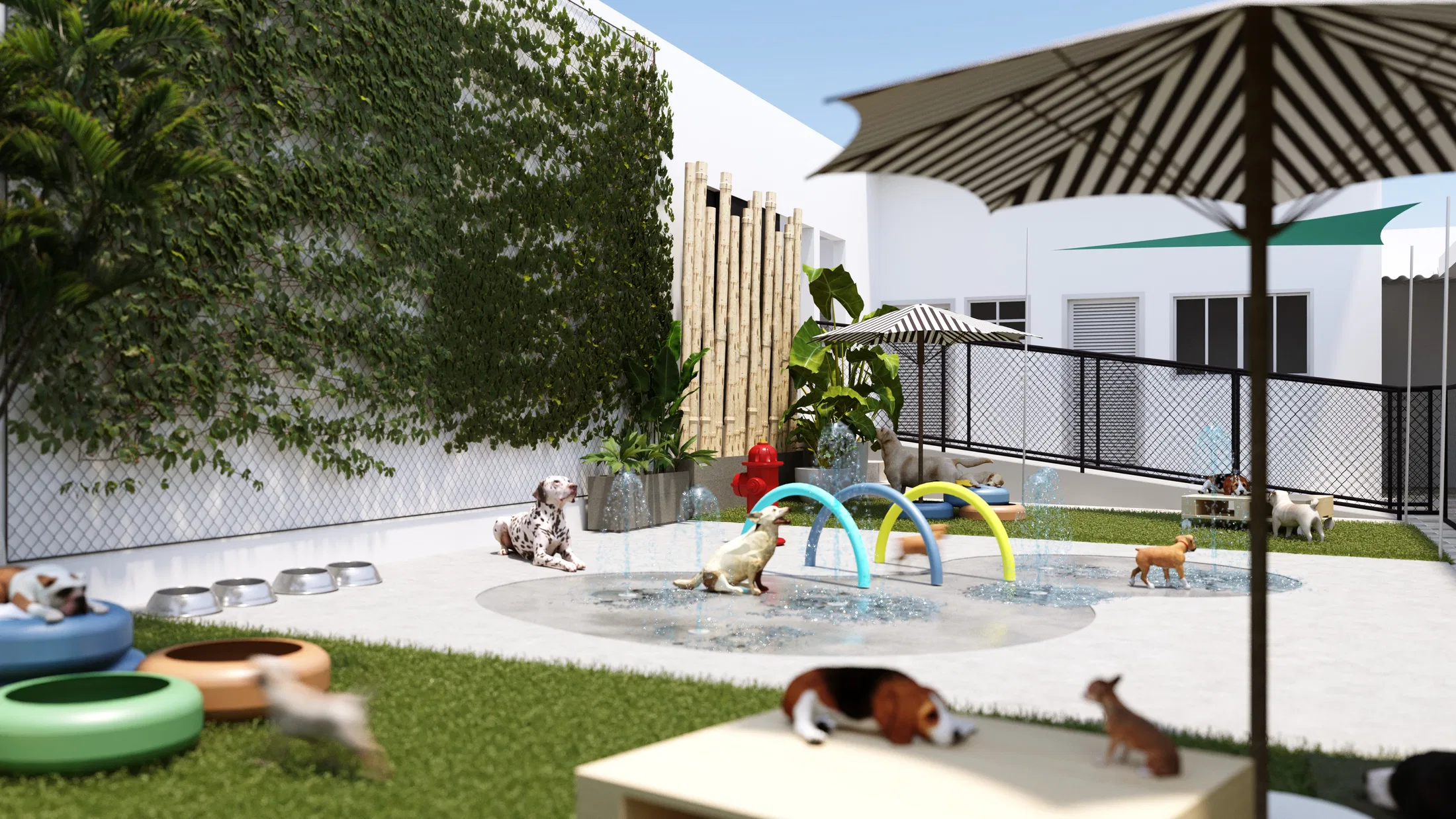 Outdoor recreation yard with artificial turf, arched water jets, a striped umbrella and several dogs playing near feeding bowls.