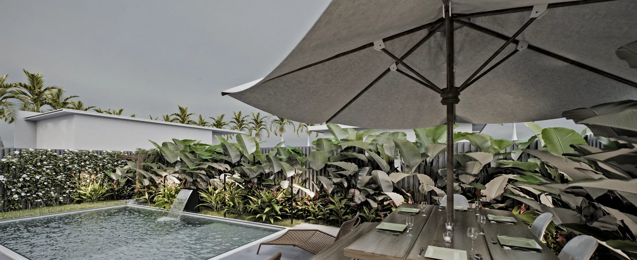 Pool with a water spout seen from a deck, a grey umbrella over a set table and a dense screen of tropical foliage behind.