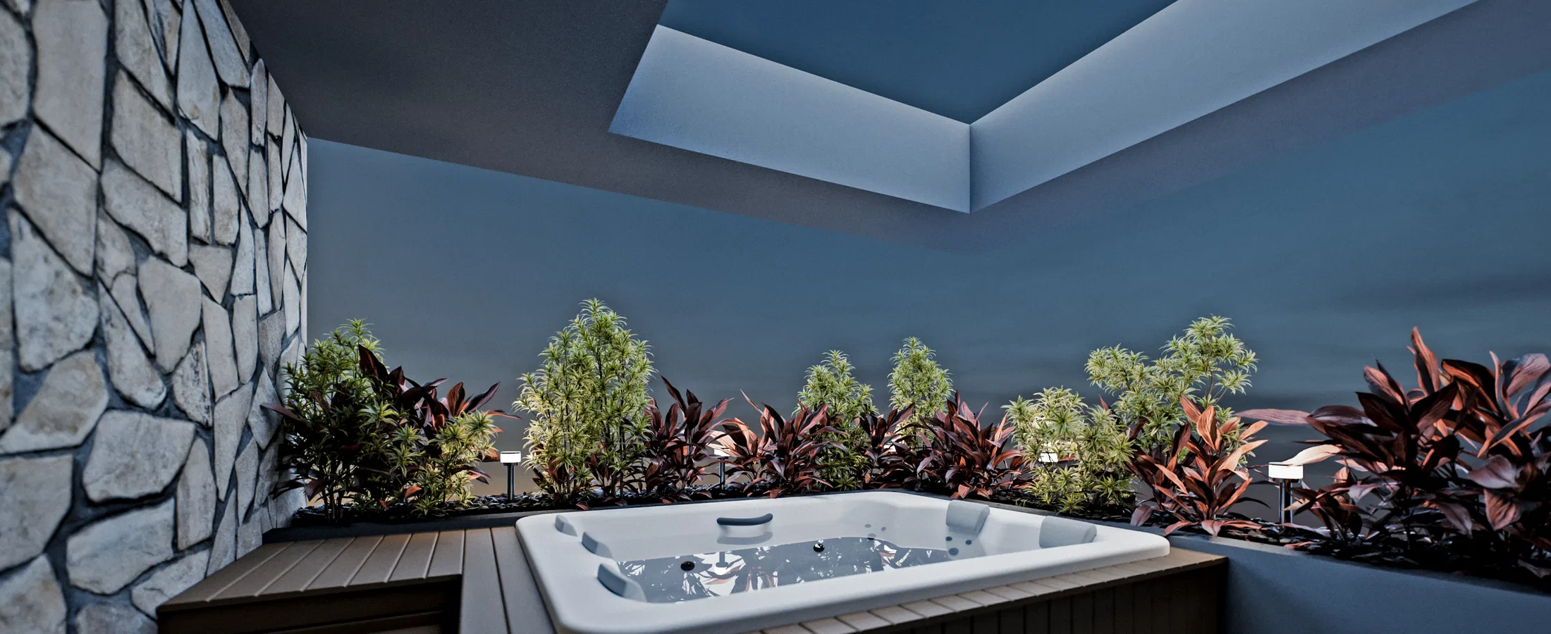 Whirlpool set into a wooden deck in a covered nook, among beds of crotons and small trees, with a stone wall and a cove-lit ceiling.