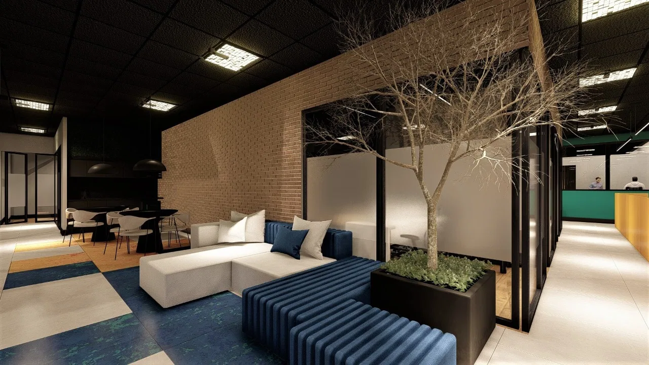 Break area with a brick wall, a white L-shaped sofa and blue bench, a decorative tree in a planter and patterned carpet flooring
