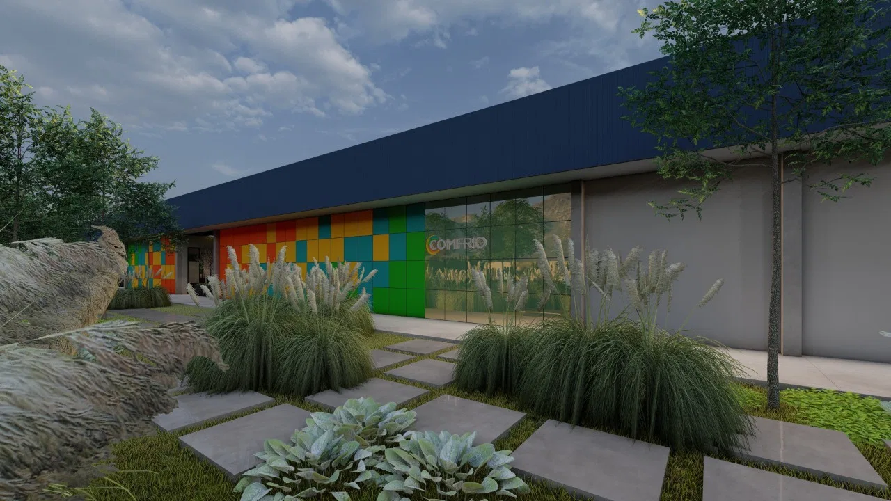 Industrial facade in dark metal cladding with a colorful checkerboard mural and mirrored glass, fronted by a bed of grasses and succulents