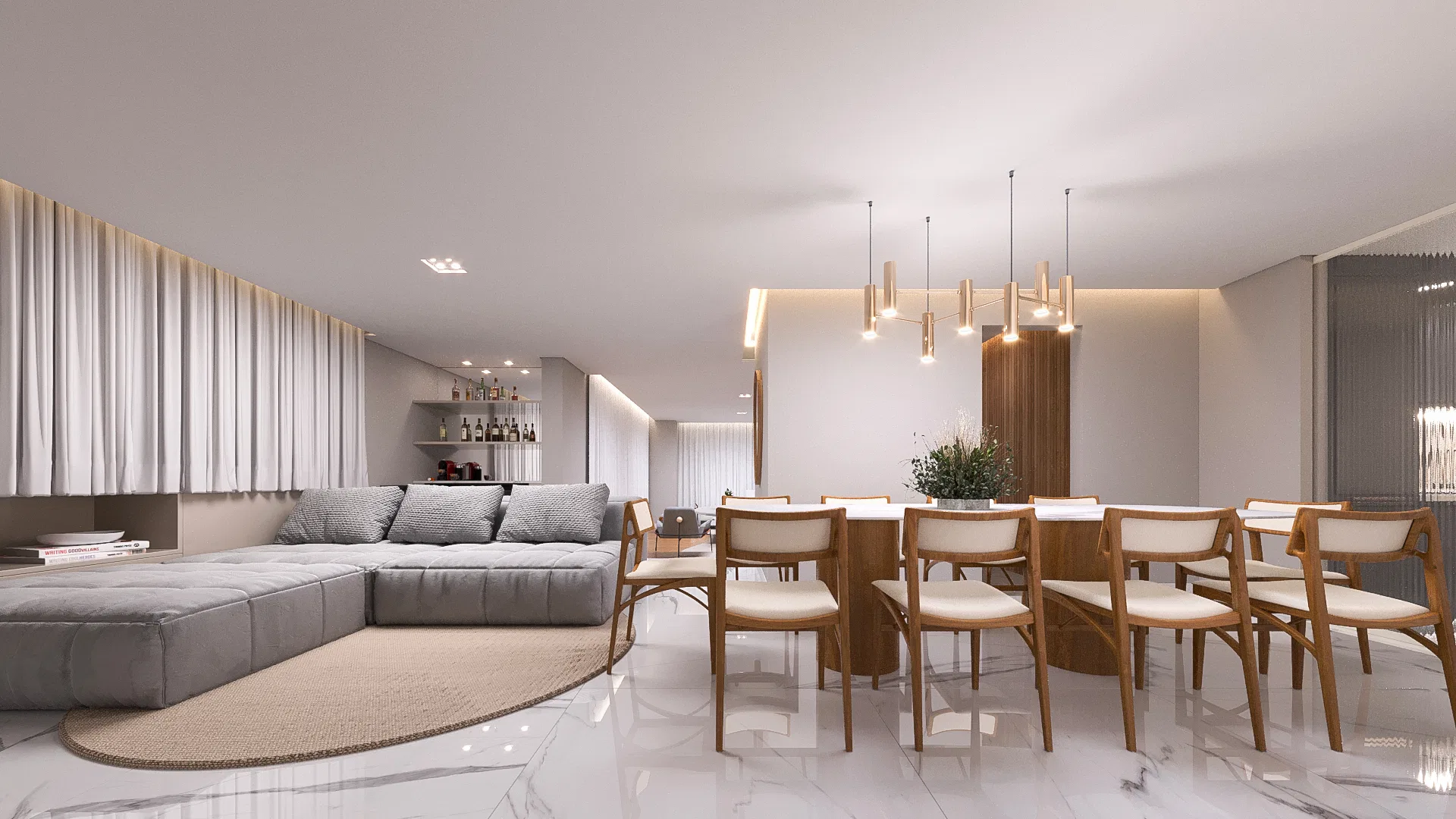 Integrated living and dining room, with a grey modular sofa on a round rug and a wooden table with brass pendants