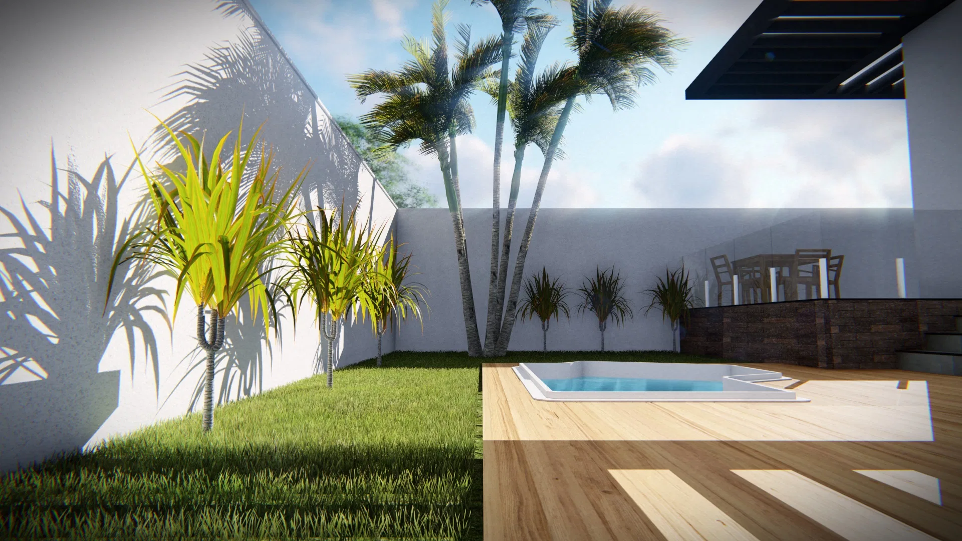 Grass strip with yellow-green dracaenas shaded by the wall, tall palms and the pool edge meeting the wood deck