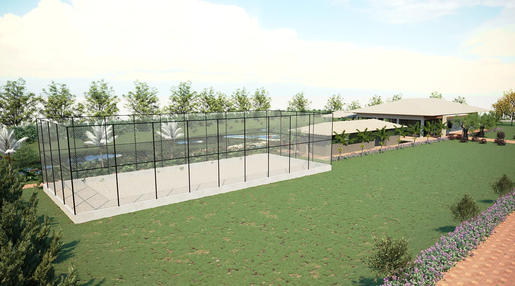 A sports court enclosed by tall fencing, with a pond and gazebo behind and a strip of purple flowers edging the lawn.