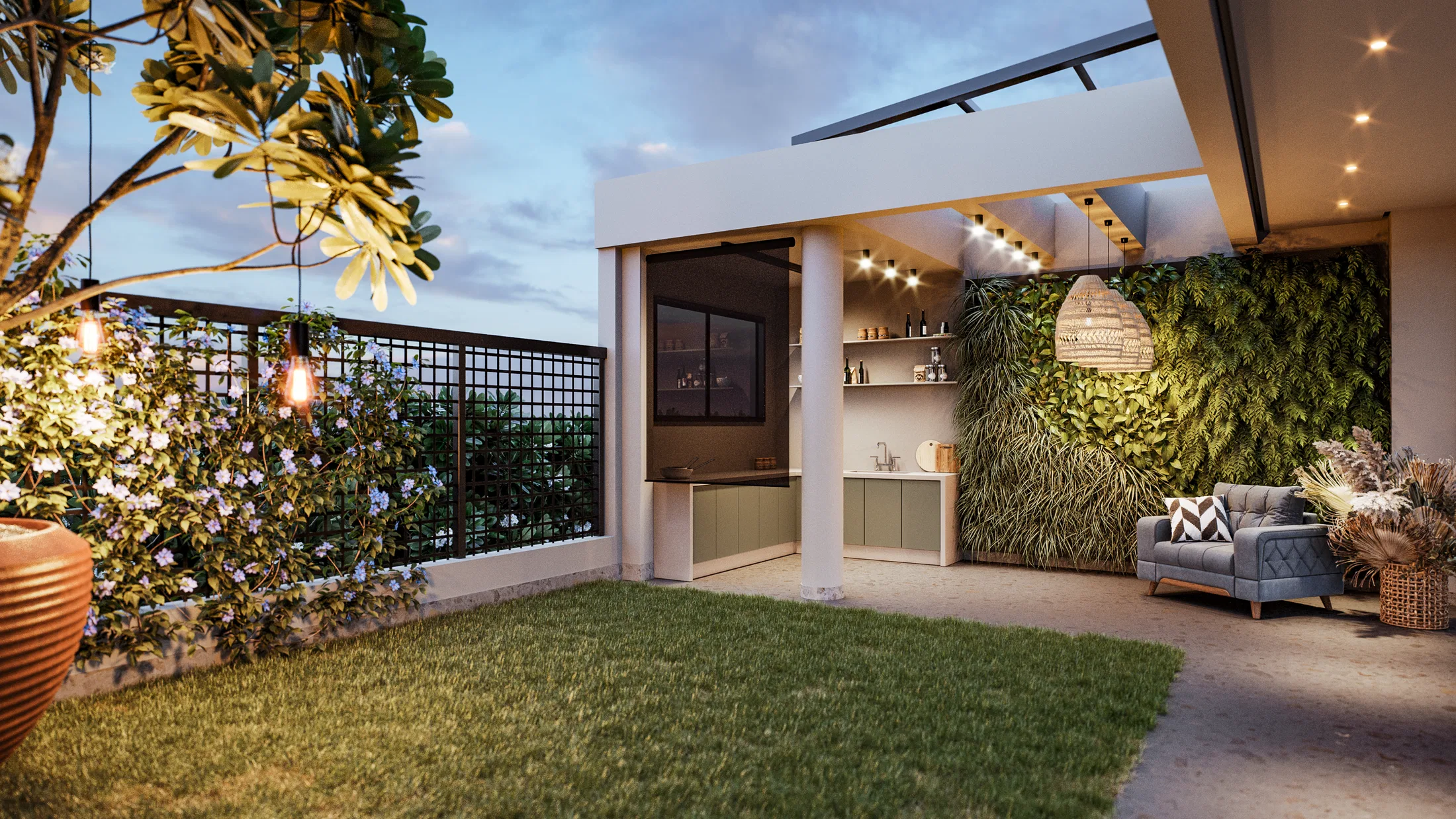 Terrace at dusk with a lawn, string lights over a flowering shrub, an outdoor kitchen with green cabinets and a living wall behind.