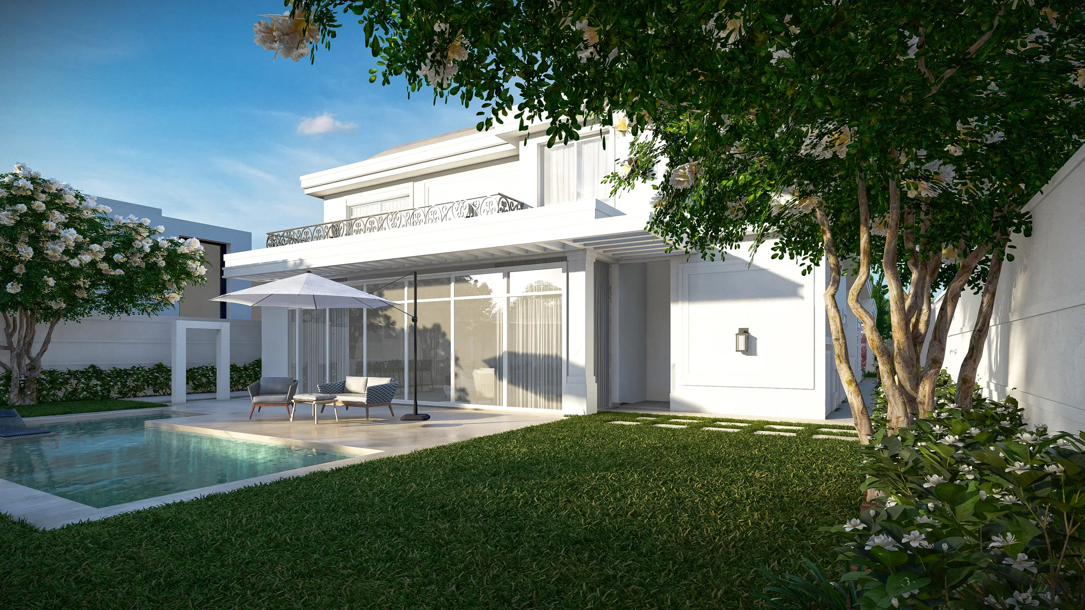 Rear of the two-storey house with an iron-railed balcony, a pool with an umbrella and a white-flowering tree over the lawn