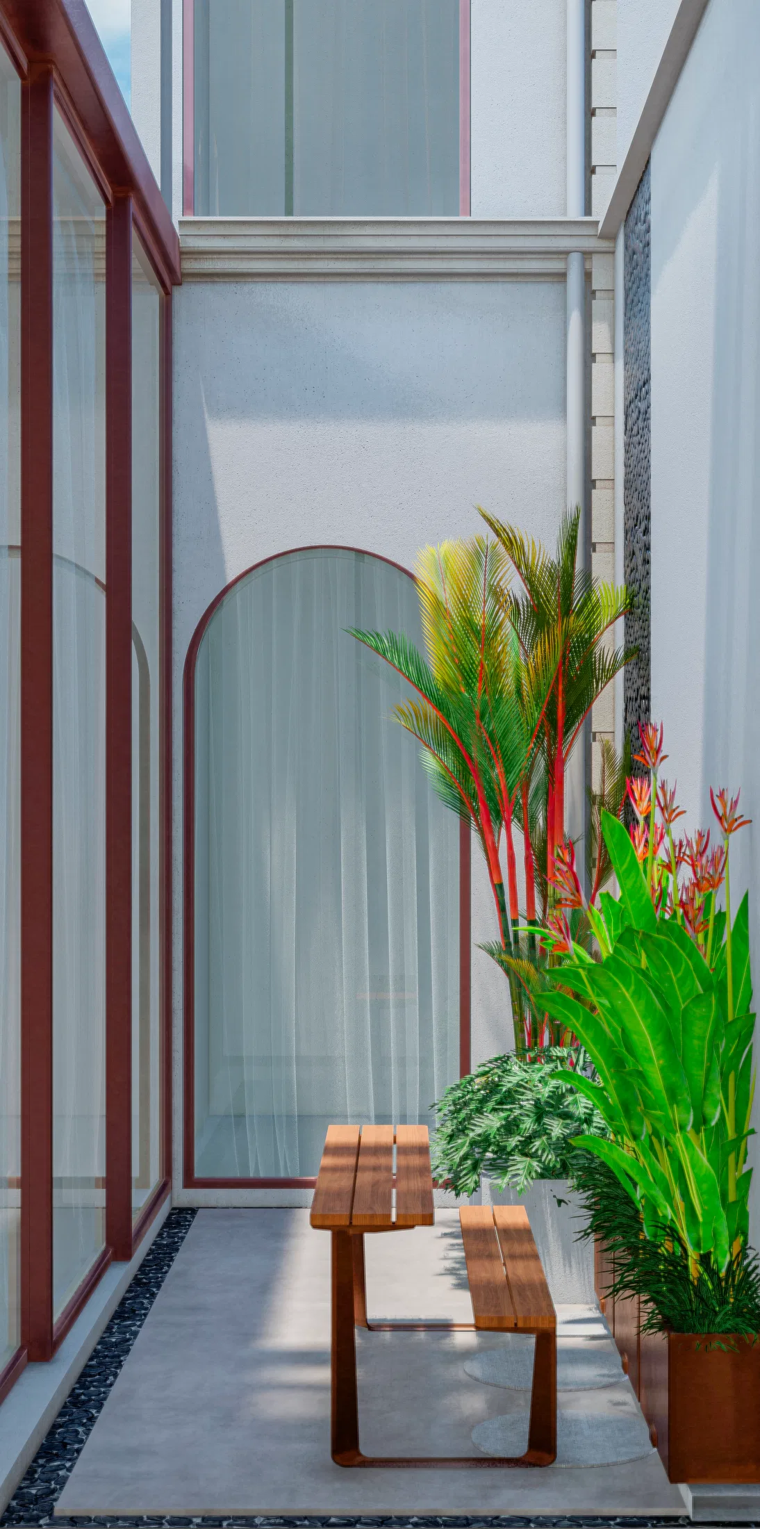 View of the same courtyard with an arched glass door in a terracotta frame, ringed by red palms, heliconias and pots of tropical foliage
