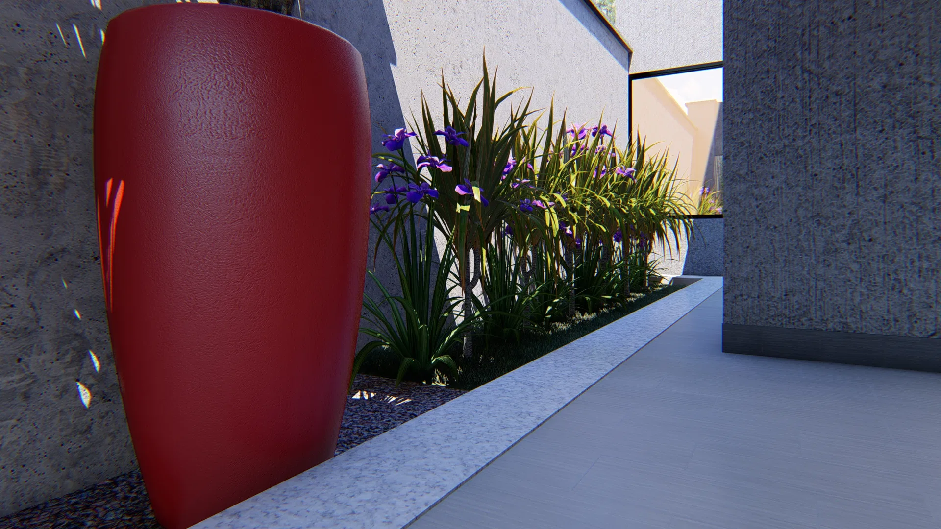 Red cylindrical planter beside a bed of purple iris and ornamental grasses along the concrete wall