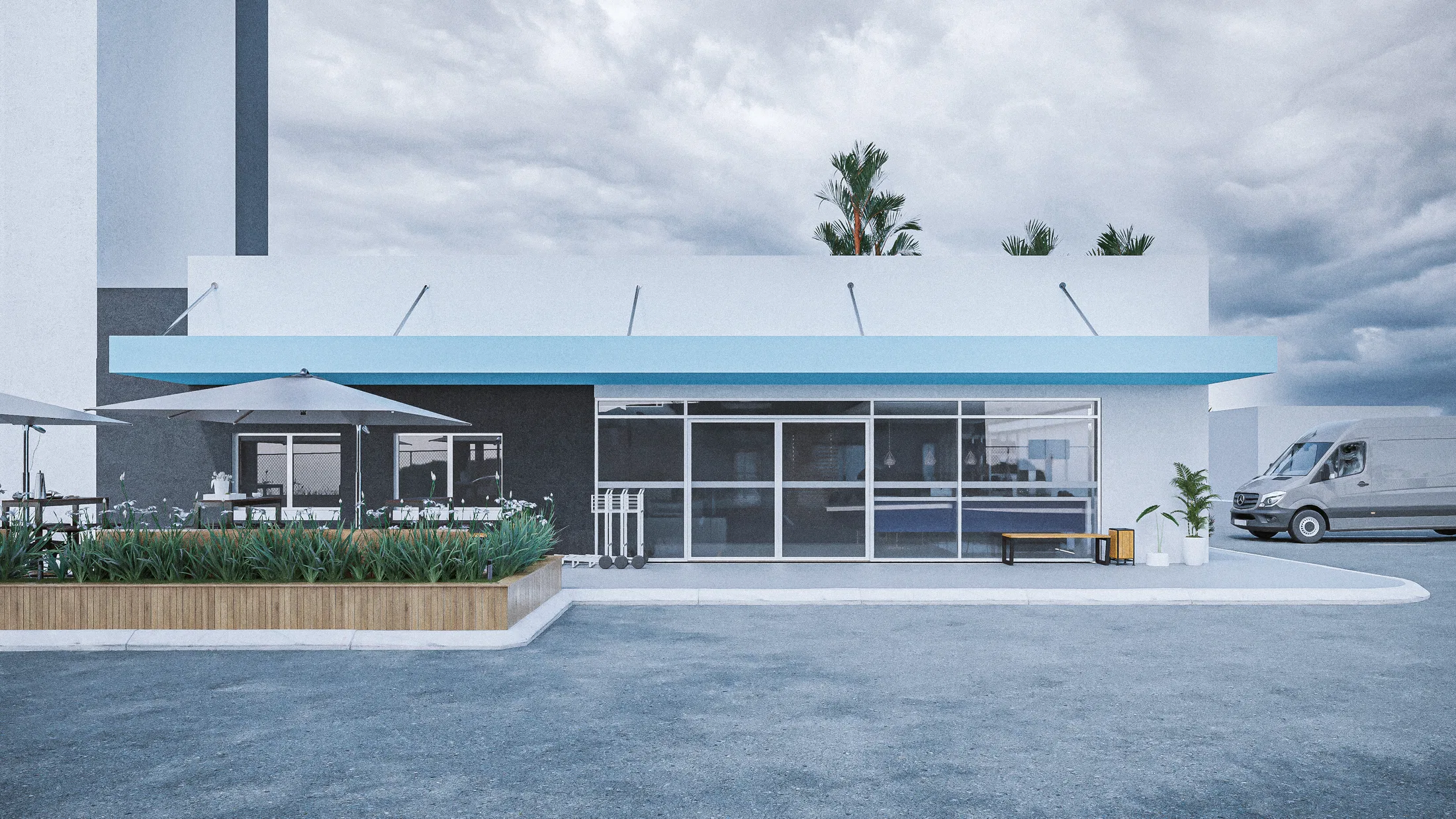 Frontal elevation of the glazed café pavilion with a blue awning and a parasol terrace behind a bed of grasses, on an overcast day