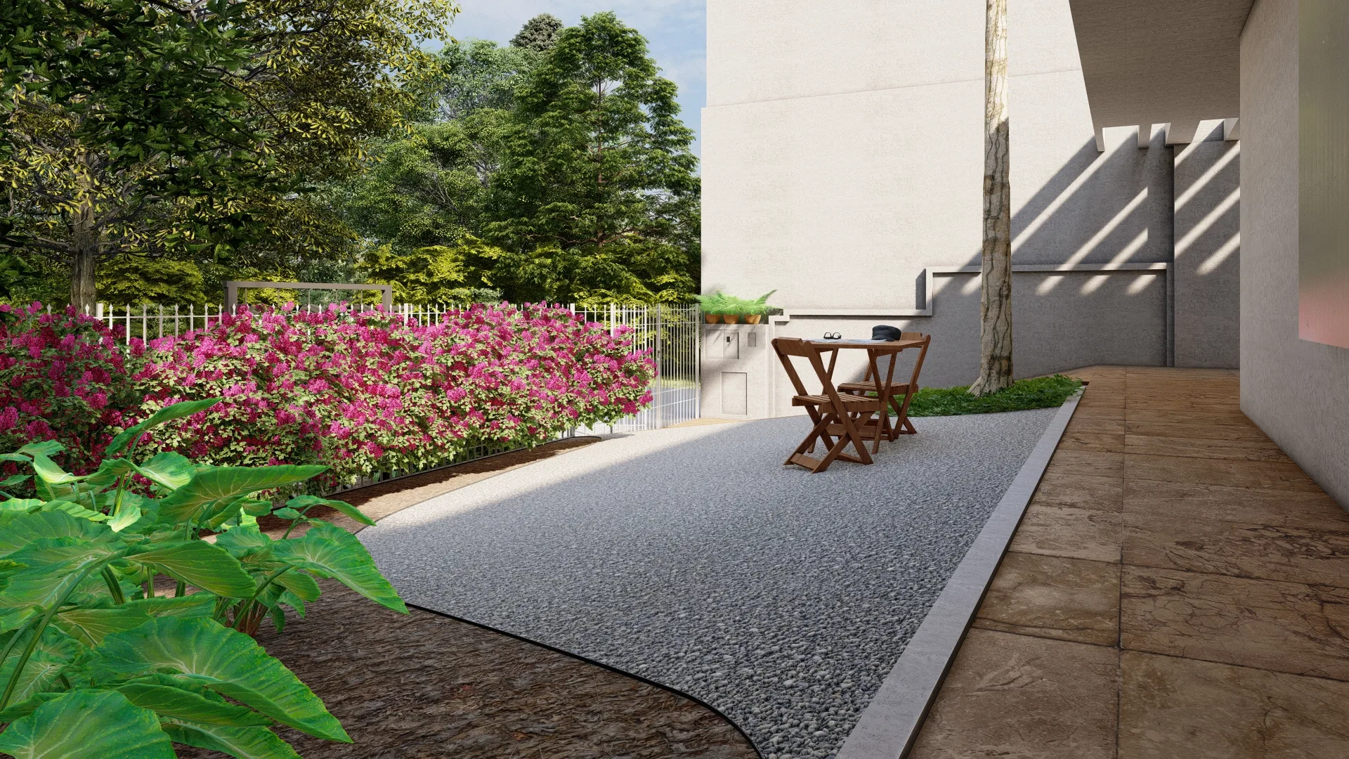 Outdoor corridor with a gravel floor, wood chairs, a pink flowering hedge and a metal fence in the background