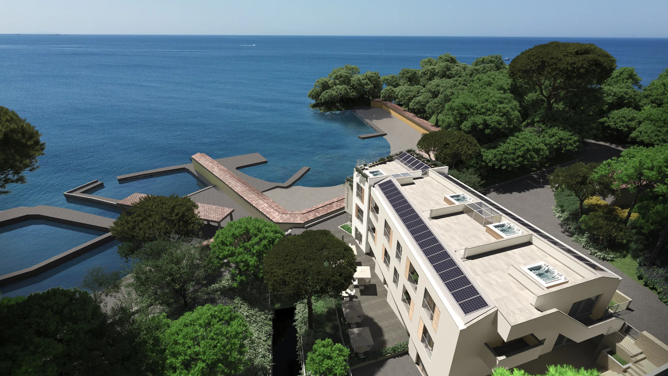 Aerial view of the building with rooftop solar panels beside a rocky cove where wooden piers reach into the blue sea