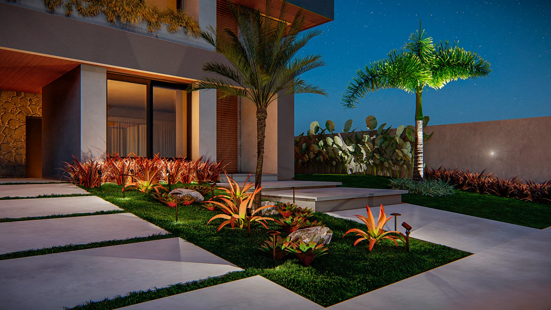 Night side garden with large-format paving over grass, a bed of orange bromeliads, decorative stones and a palm beside the lit boundary wall