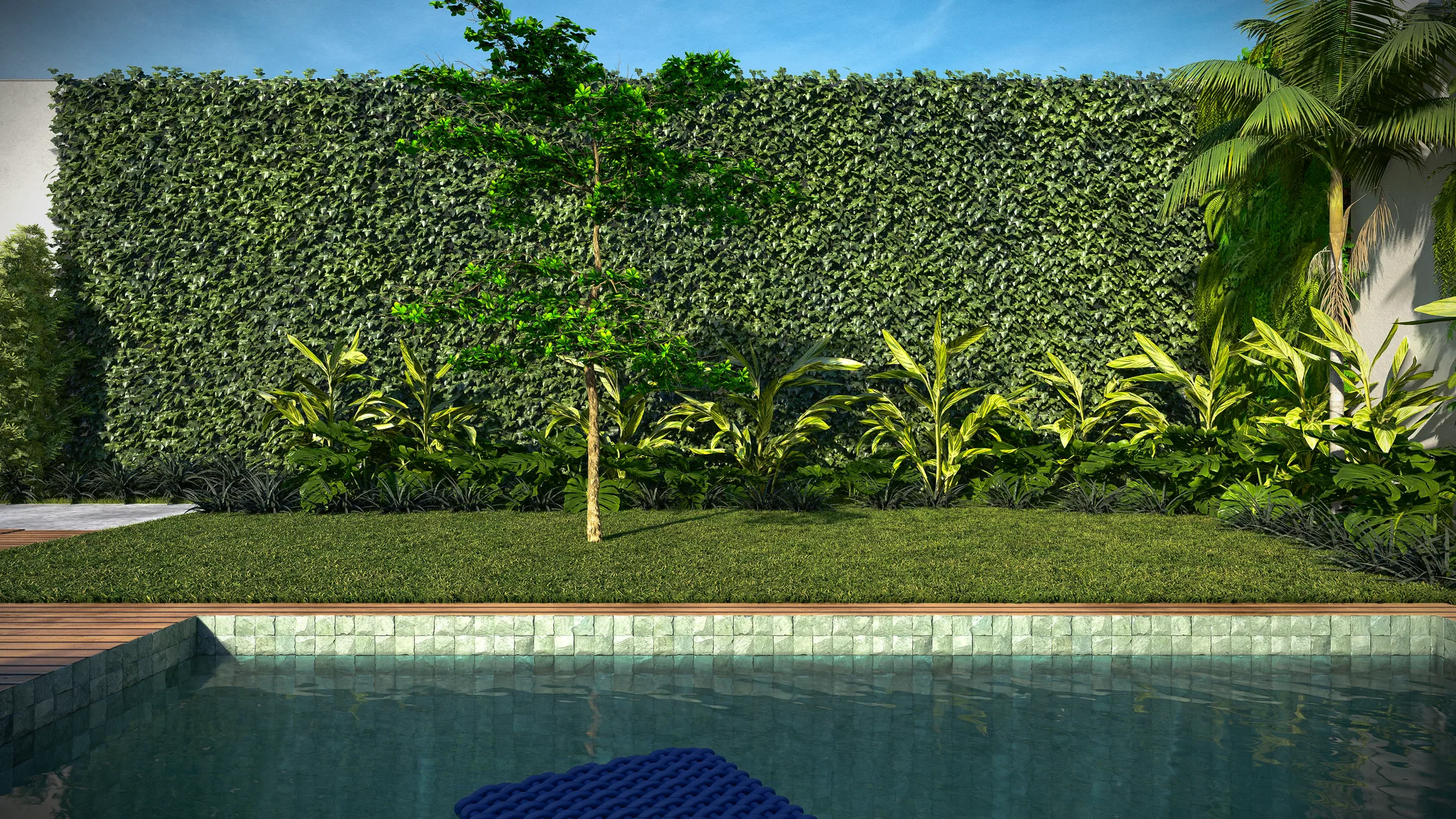Borda de piscina de pastilha com faixa de gramado, muro tomado por trepadeiras densas, uma árvore central e maciço de folhagens tropicais.