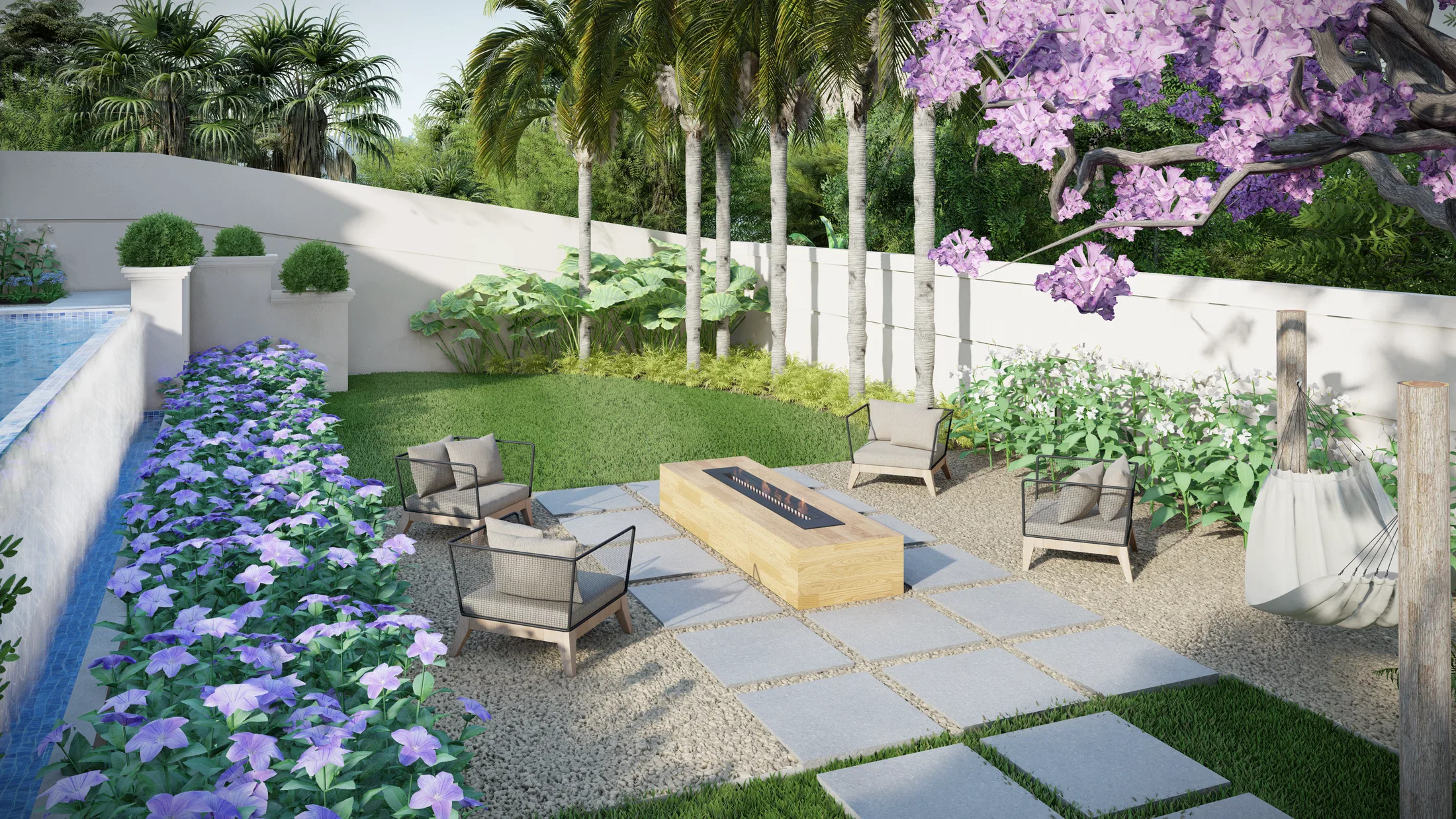 Outdoor lounge with a linear wood fire feature, wicker armchairs on stone and gravel, palms and a bed of blue flowers along the pool