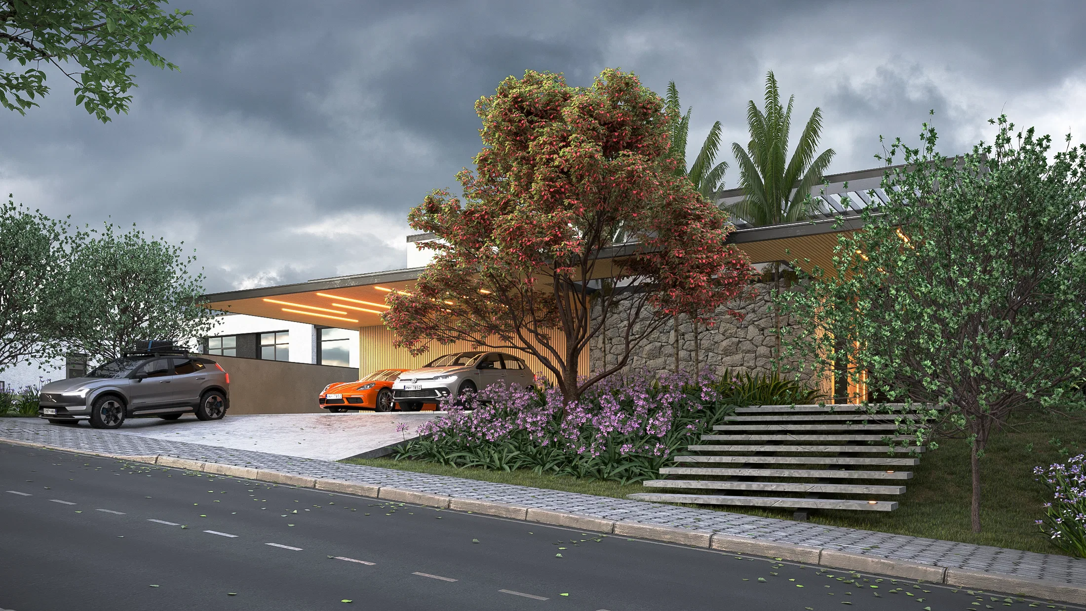 Side view of the residence at dusk, with a wide stone stairway rising between purple flowering shrubs and a reddish tree canopy