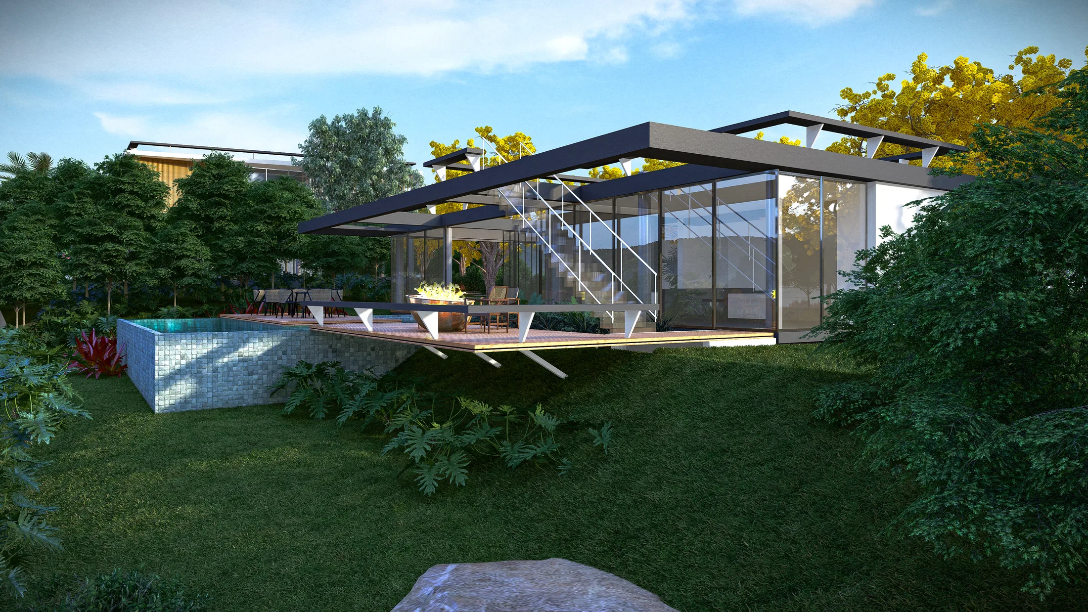 Rear garden at dusk with a blue-tiled pool, a deck lounge with a fire feature and the glass pavilion framed by tropical planting