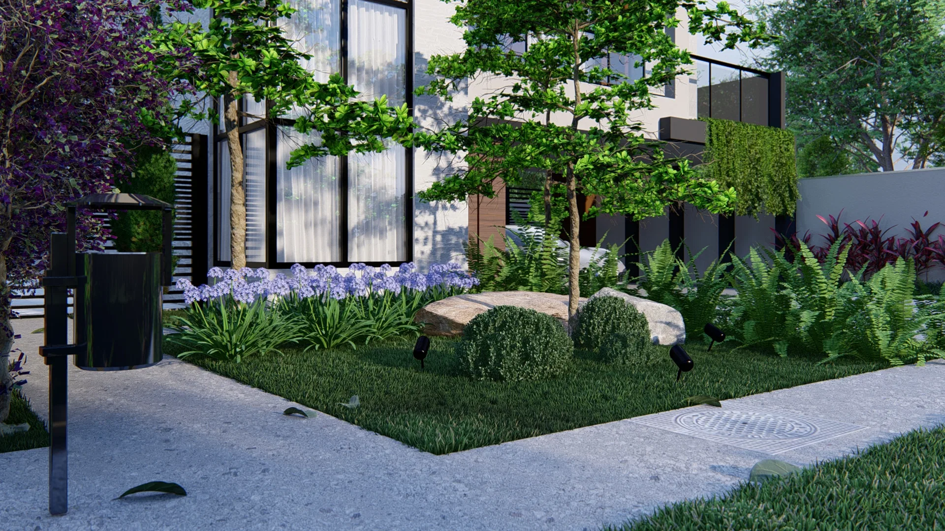 Corner planting bed with boulders, ferns, blooming agapanthus and a purple-leaved shrub beside a stainless steel outdoor trash bin