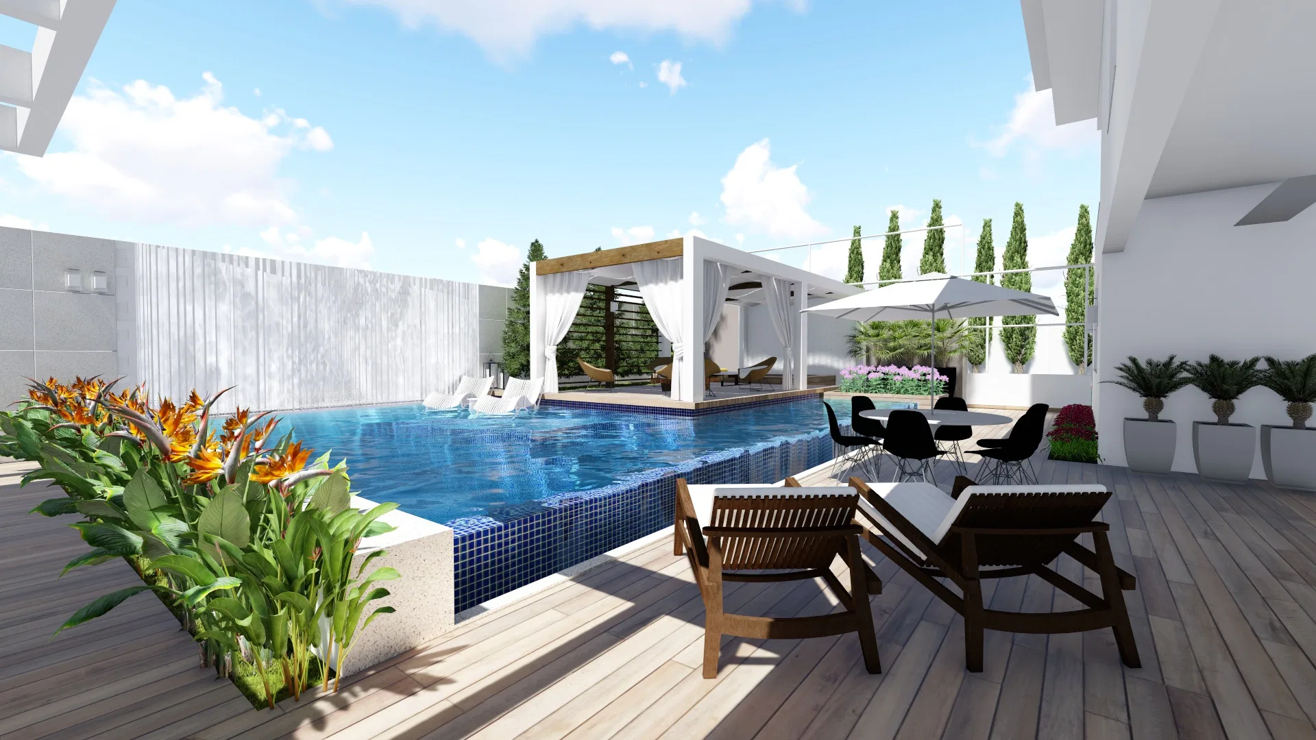 Pool area with a wooden deck, a pergola with white curtains, loungers, a dining table and orange tropical flowers in a planter