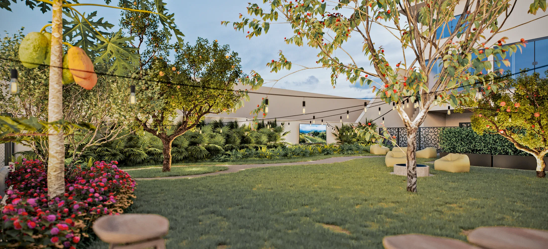 Garden at sunset with a papaya tree and a fruit tree, a string of lights, bean-bag chairs and a landscape panel set into the wall.