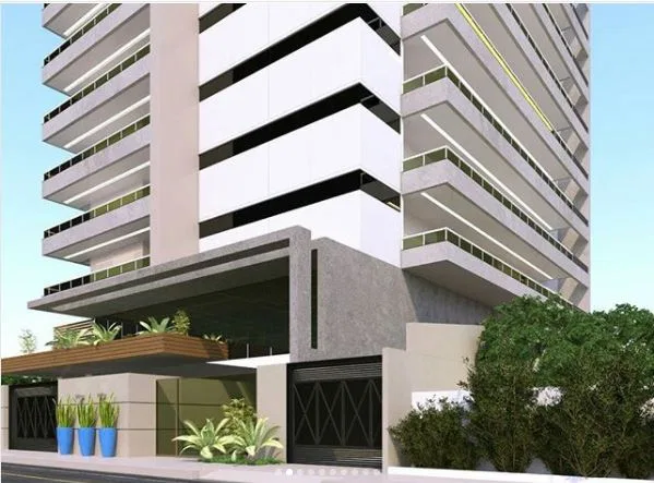 Angled view of the residential building with a black-and-white striped tower behind and greenery along the entrance wall