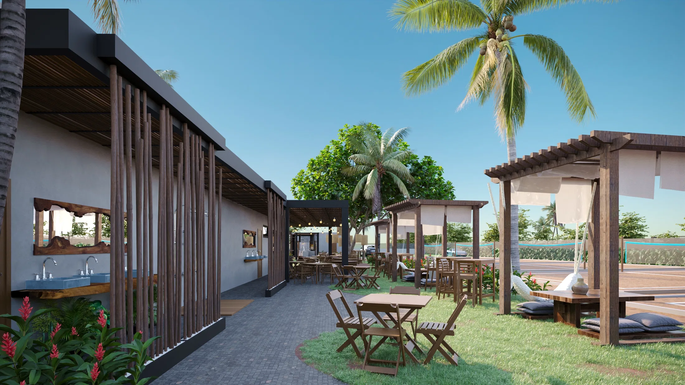 Side view of the building with a vertical-slat screen and mirrored washbasins, a paved path, folding tables and a coconut palm beyond