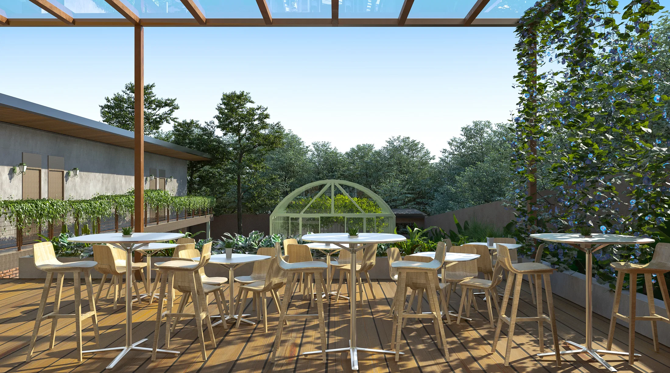 Wooden terrace under a pergola with round high tables and light-wood stools, the arched greenhouse behind and climbing plants to the right