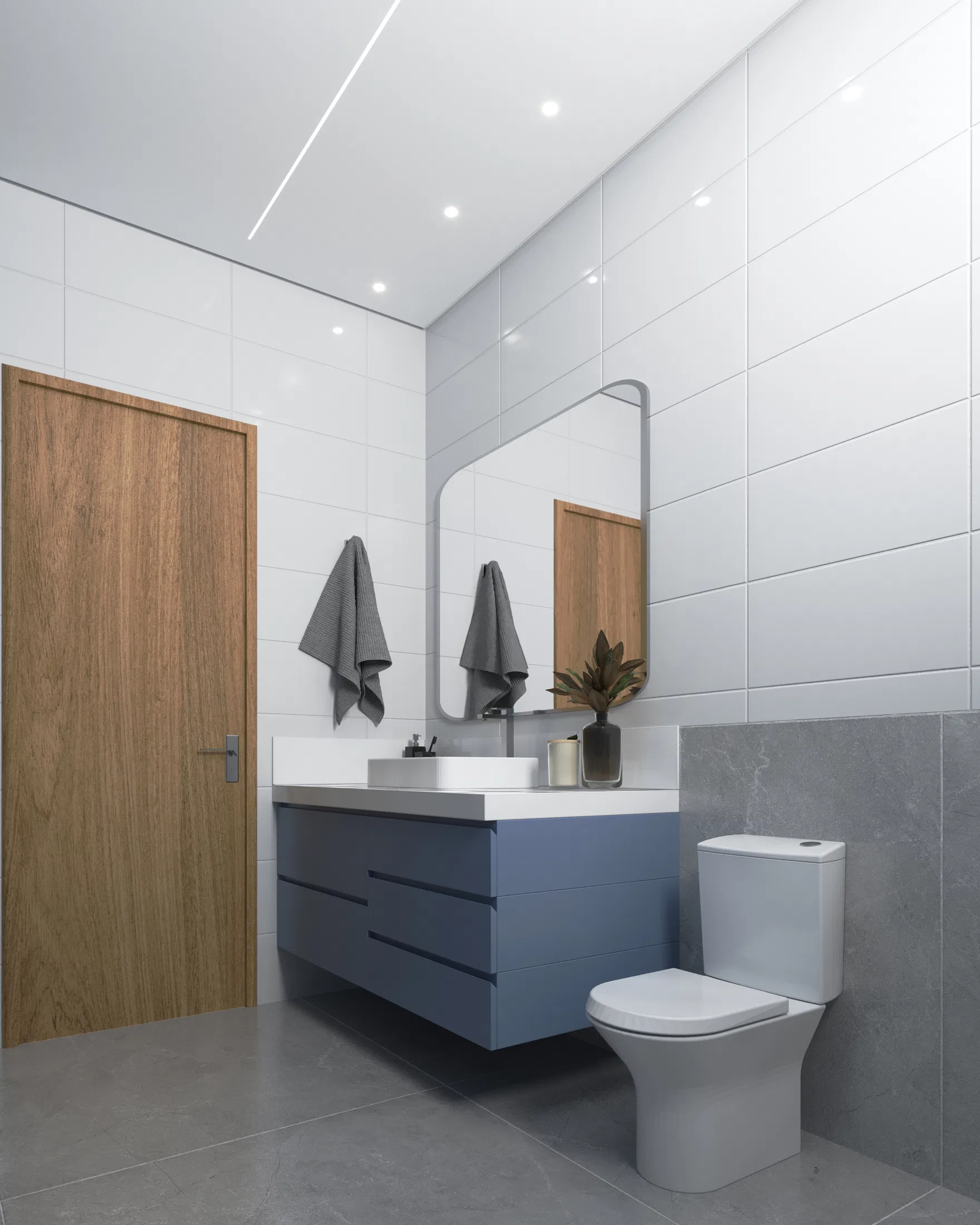 Bathroom with a suspended petrol-blue cabinet and white basin, a round-cornered mirror, white and gray tiling, towels and a toilet