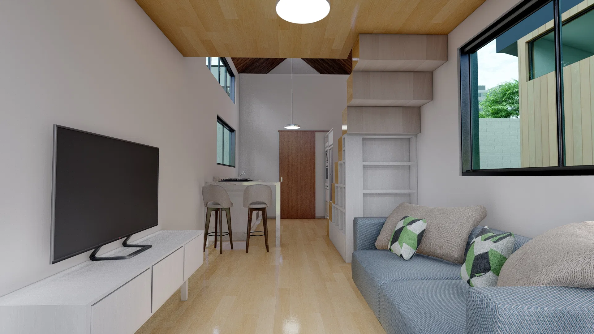 Narrow living area with a grey sofa, a low TV stand, kitchen stools further back and the mezzanine structure suspended above the pantry