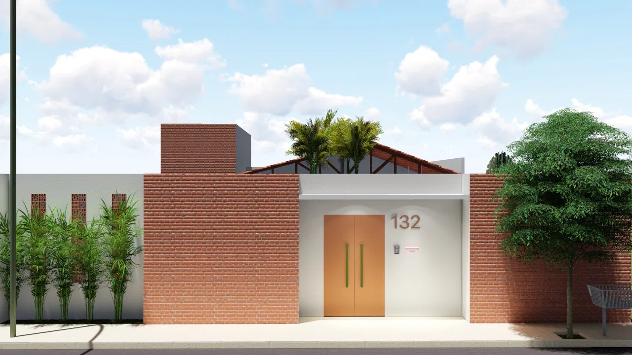 Residential facade in exposed brick with a wood gate, green vertical handles and the number 132, flanked by bamboo and a tree with a bench