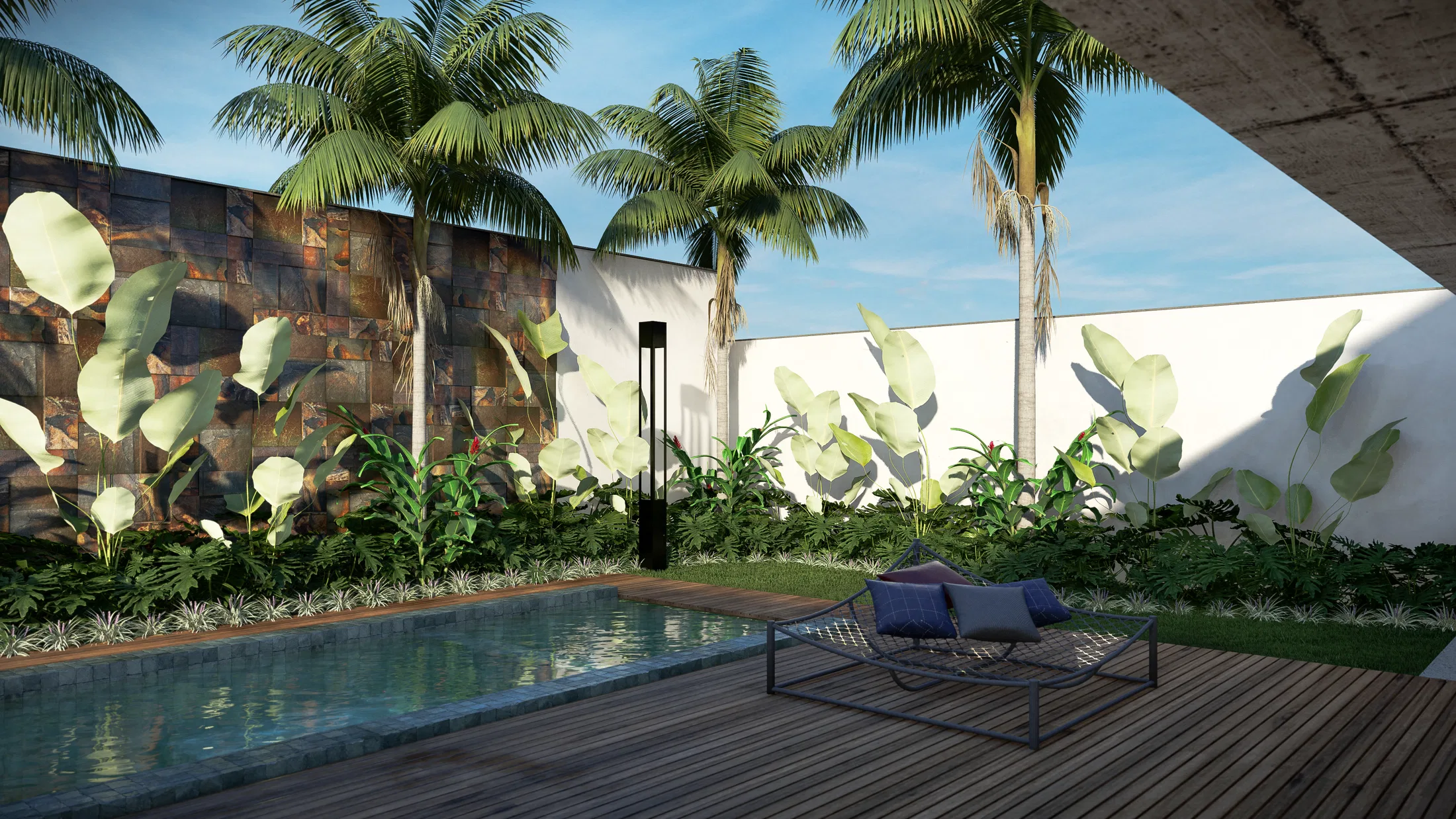 A timber deck with a double daybed and cushions, a decorative stone wall, palms and dense planting around the pool.