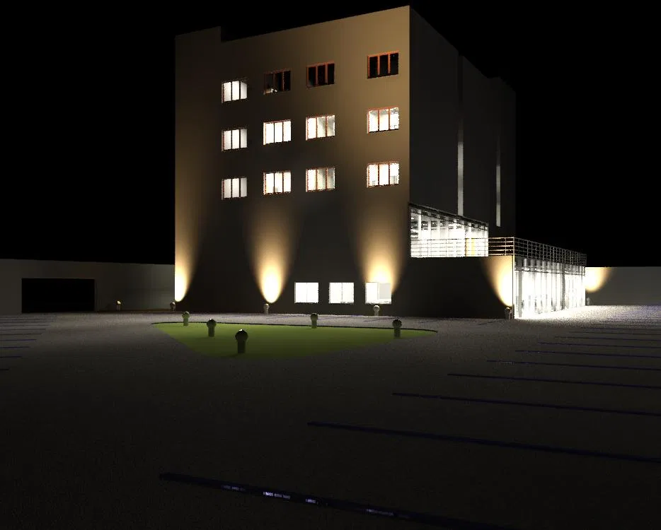 Night facade of a multi-storey building with lit windows, base floodlights, a glazed annex at right and a parking lot in the foreground